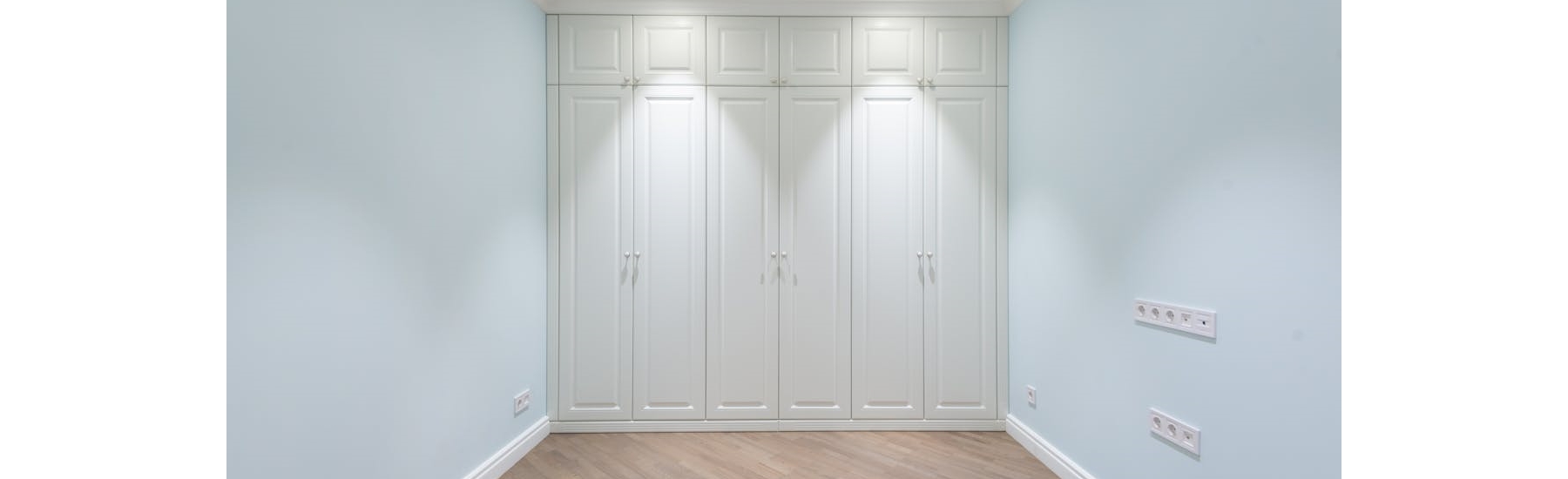 Modern light-coloured fitted wardrobe doors in a small bedroom creating a bright and spacious feel