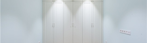 Modern light-coloured fitted wardrobe doors in a small bedroom creating a bright and spacious feel