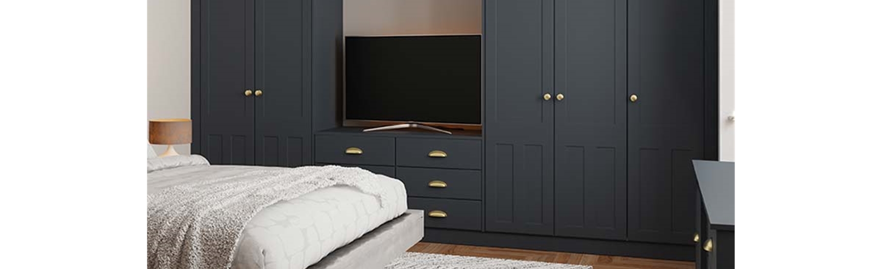 Modern bedroom with dark blue wardrobes, a large TV, and a cozy bed with a textured blanket. A light gray rug and wooden floor add warmth.